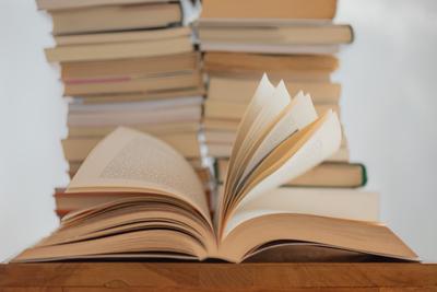 An open book with books stacked behind