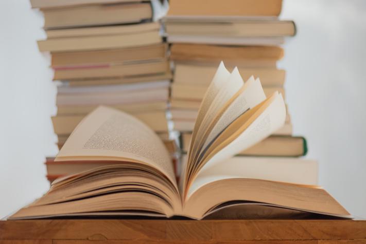 An open book with books stacked behind
